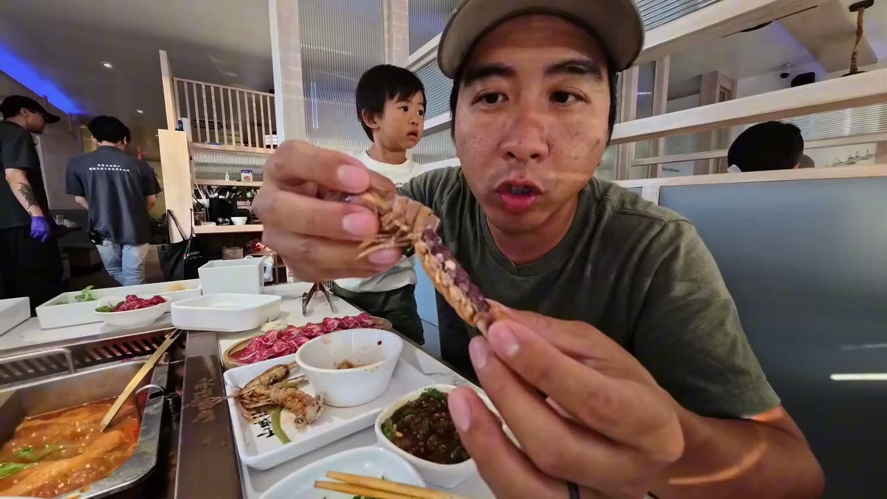 Michael holding up a cooked mantis shrimp at Chongqing Wharf while Spencer watches