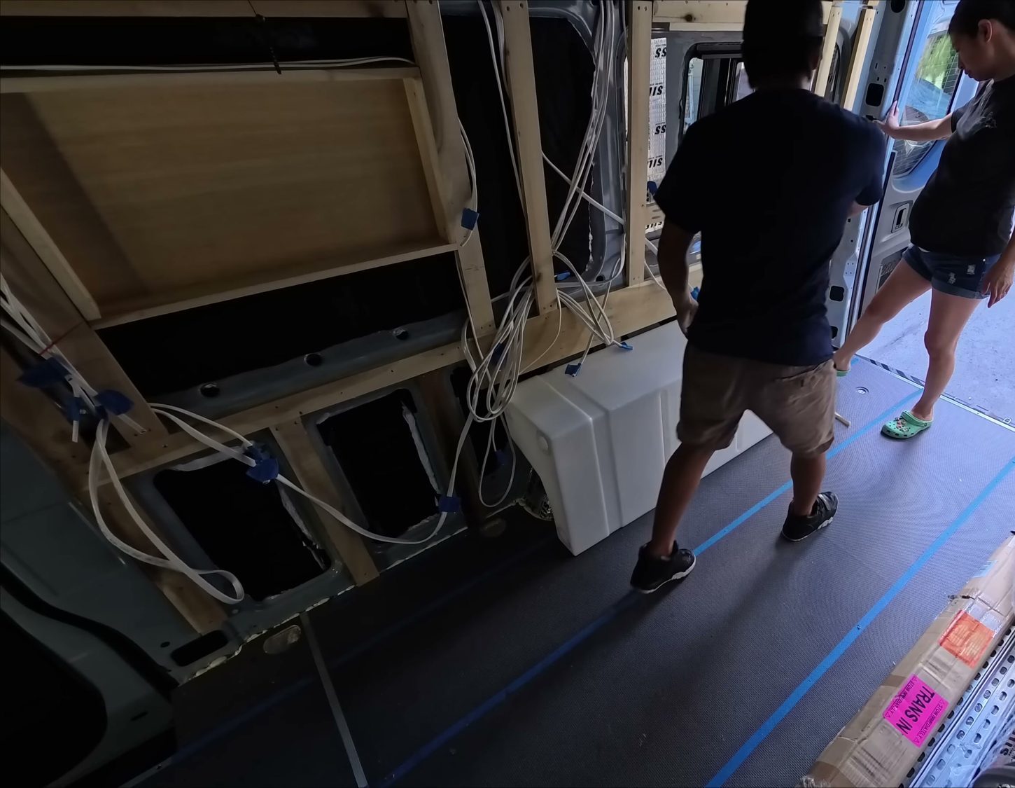 The 35-gallon fresh water tank sitting over the wheel well inside the bare van