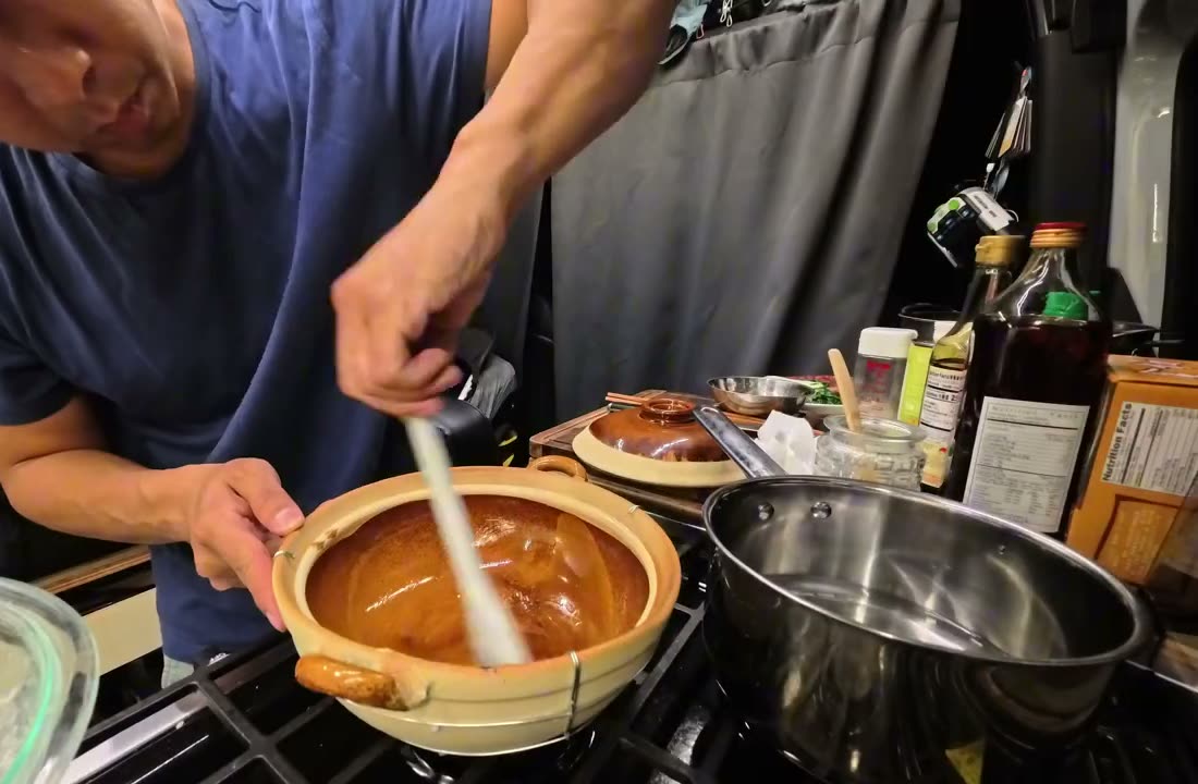 Michael brushing melted lard onto the bottom of a clay pot in the van kitchen