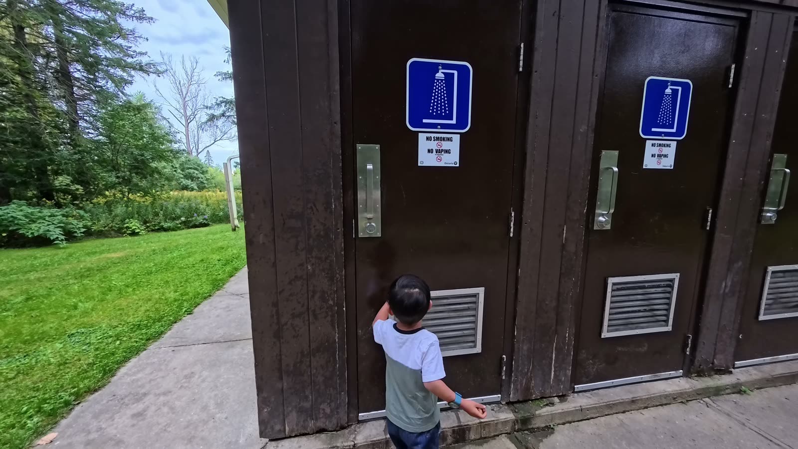 Spencer standing at the door of an individual shower stall at the Darlington Provincial Park comfort station
