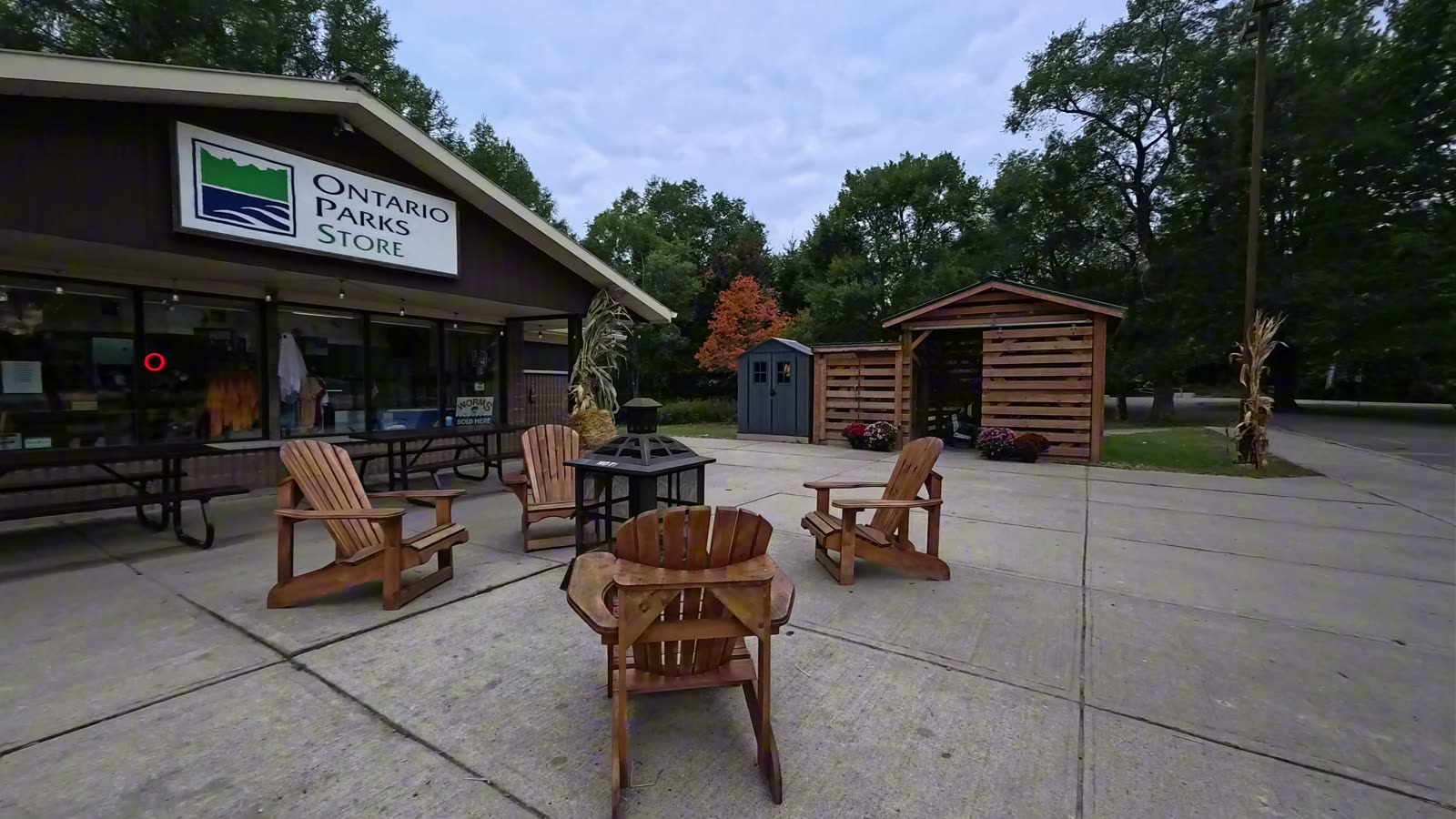 The Ontario Parks Store at Darlington Provincial Park with wooden Adirondack chairs and a fire table on the patio
