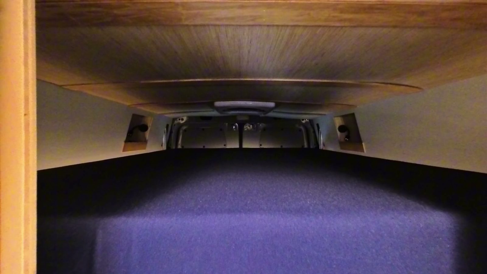 Looking up from the platform at the underside of the raised elevator bed, with the rails and the rear doors behind it