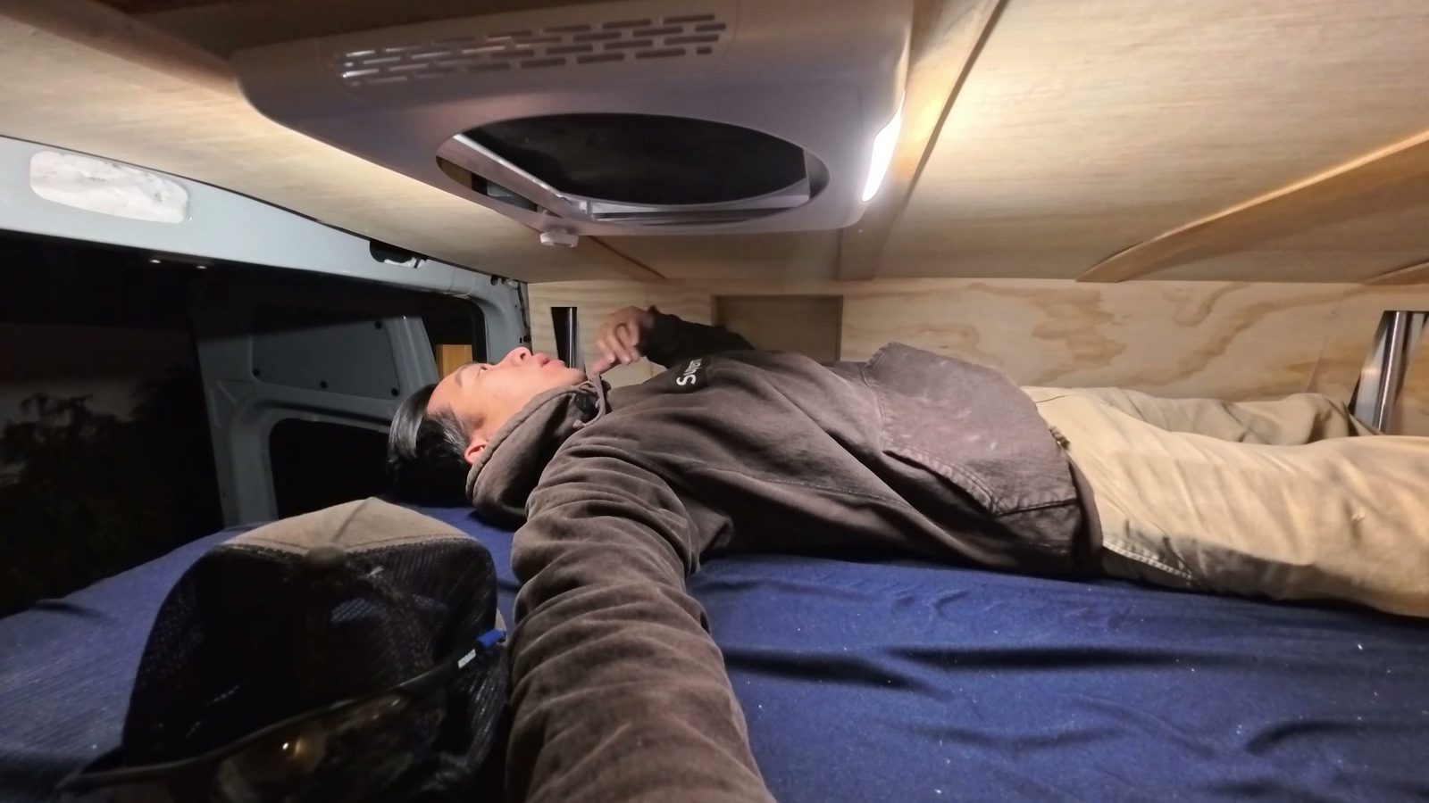 Michael lying on the new mattress on the raised elevator bed, close to the roof fan