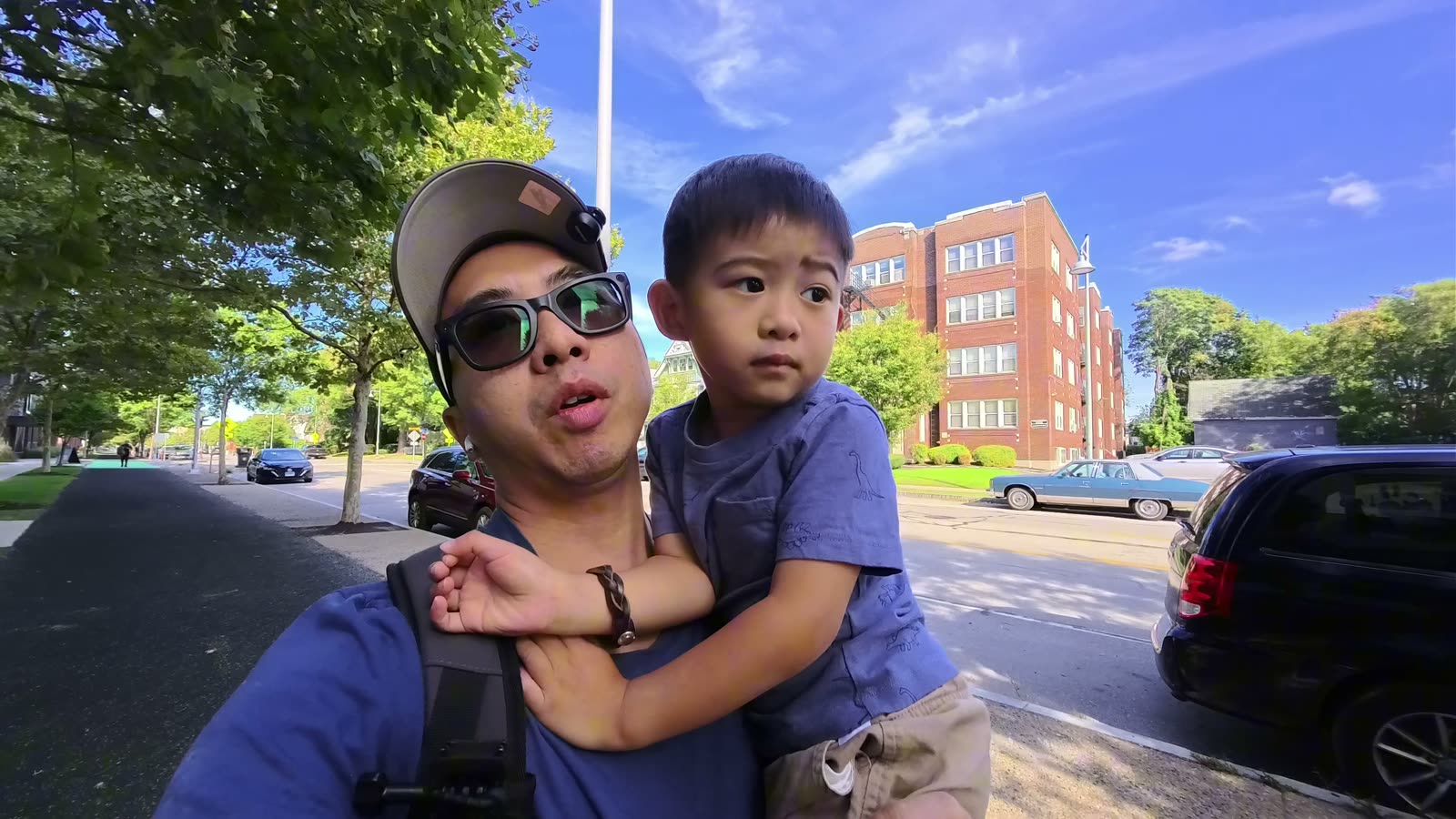 Michael carrying Spencer on a sunny street in Rochester before the drive to Canada