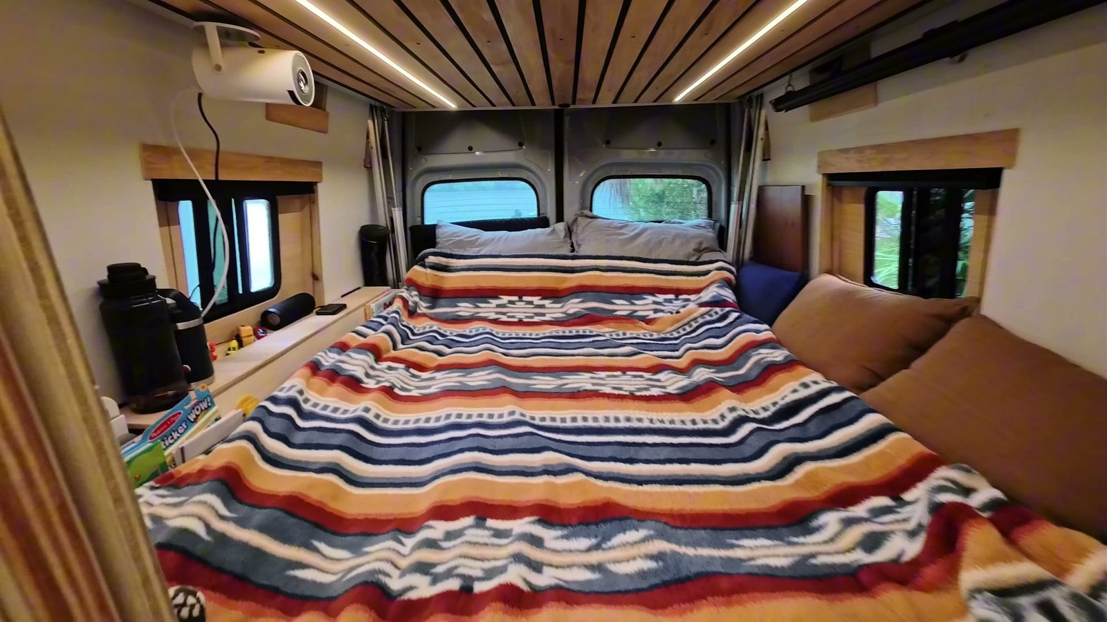 The floor sofa unfolded into a full-size bed on the platform, with a striped blanket and pillows