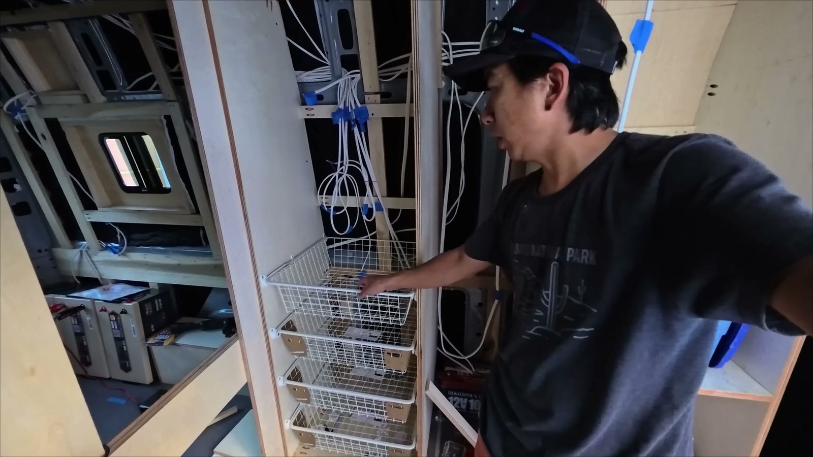 Mesh closet baskets on rails being fitted into the plywood closet during the build