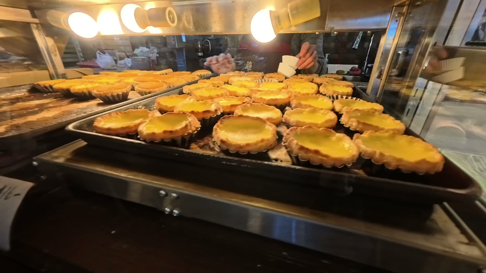 Fresh egg tarts on a tray in a bakery case