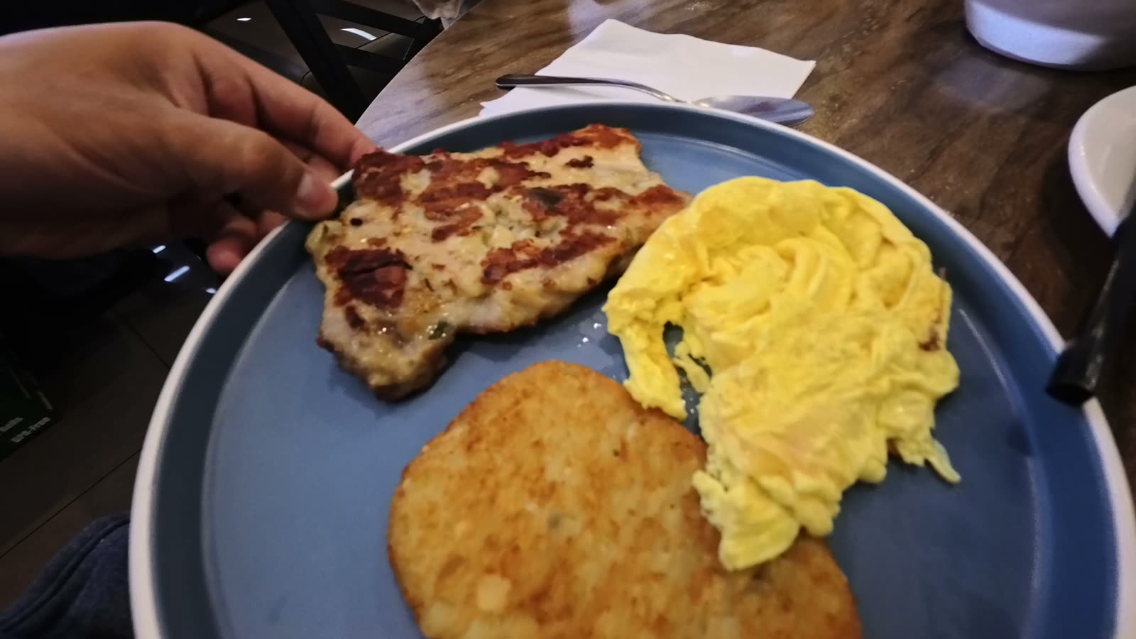 Grilled chicken, a hash brown and scrambled eggs on a blue plate