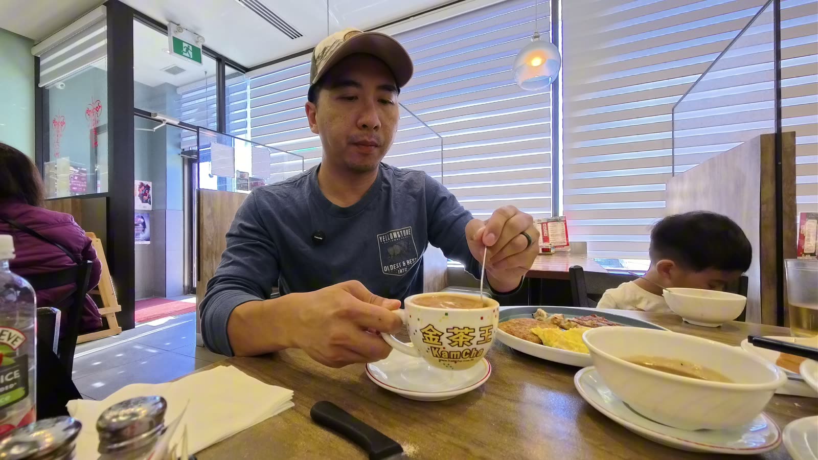 Michael stirring a cup of Hong Kong milk tea at the table