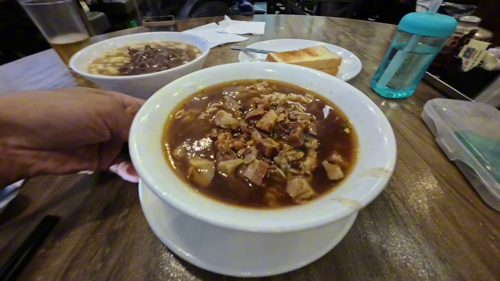 A close-up bowl of diced pork noodles in a dark, rich soup