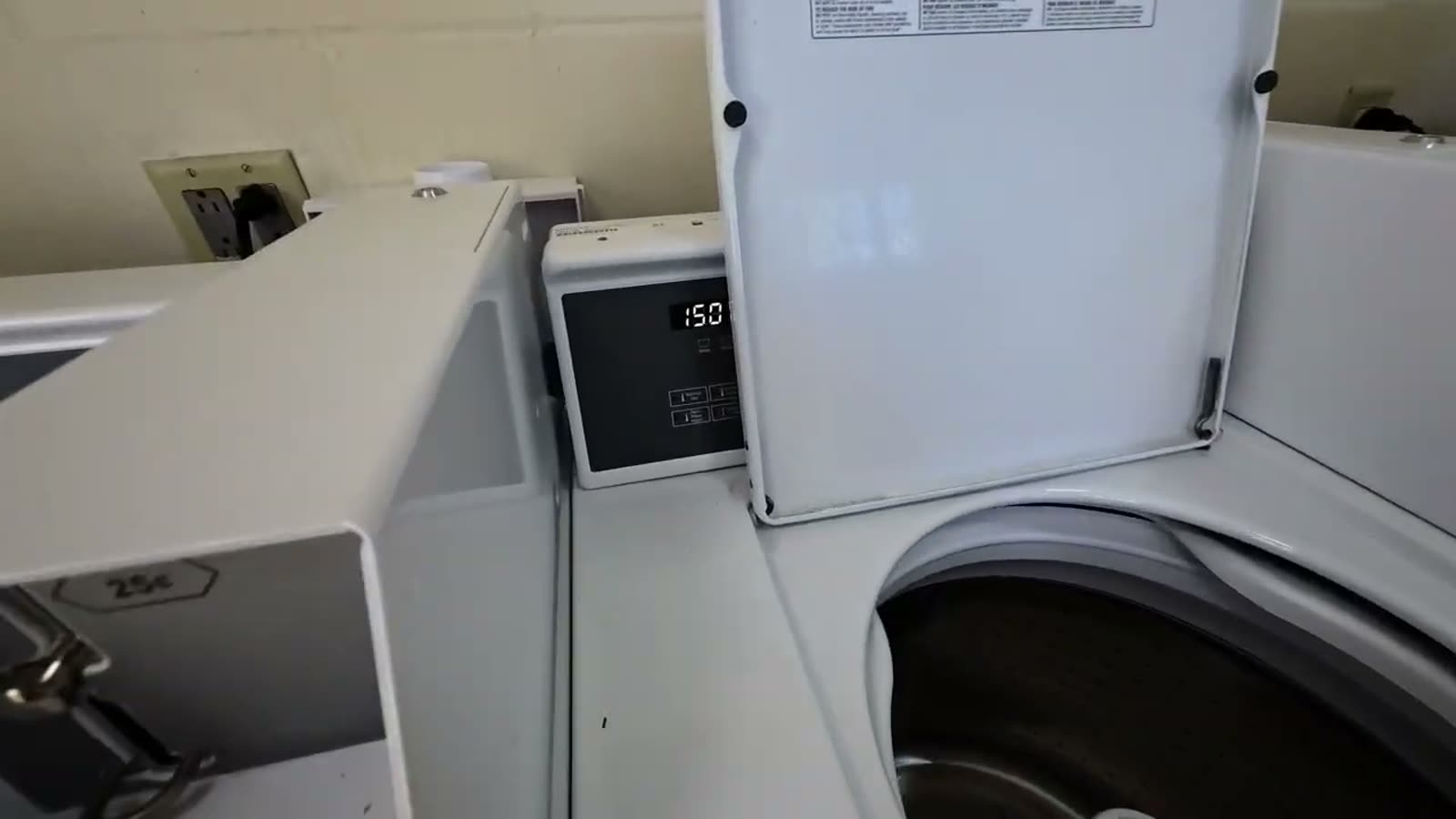 A campground washing machine with its lid open and a display showing 1.50