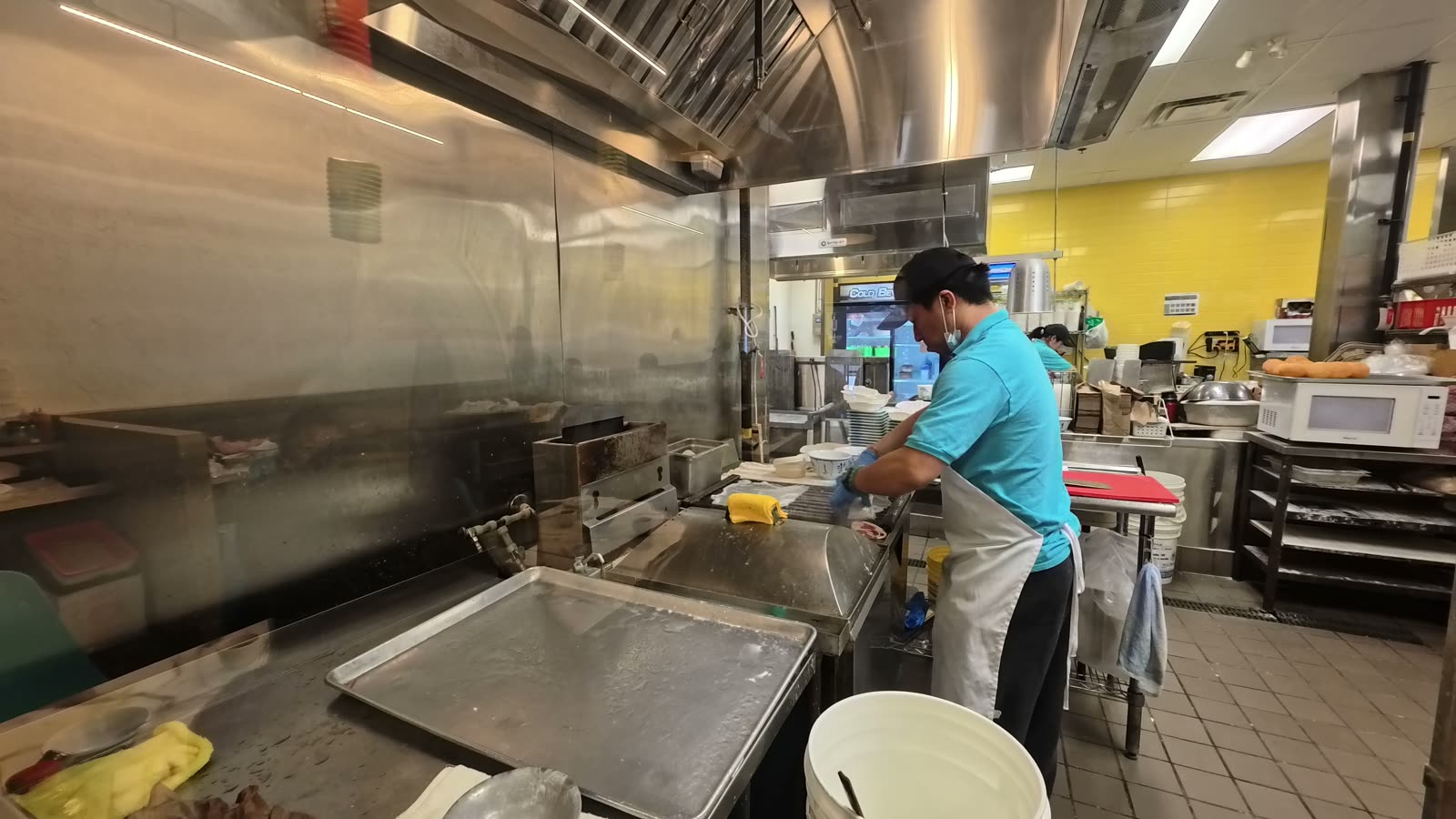 A cook working in the open kitchen at Sam’s Congee Delight, seen through the big glass window