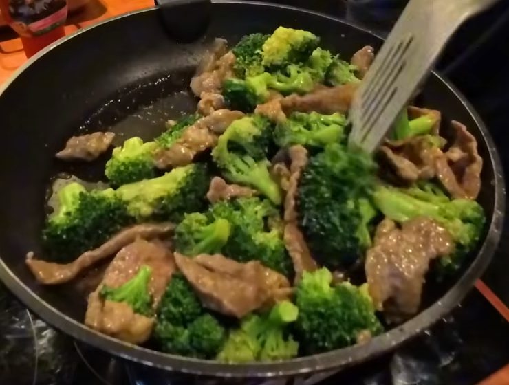 Beef and broccoli being stir fried in a pan in the van kitchen