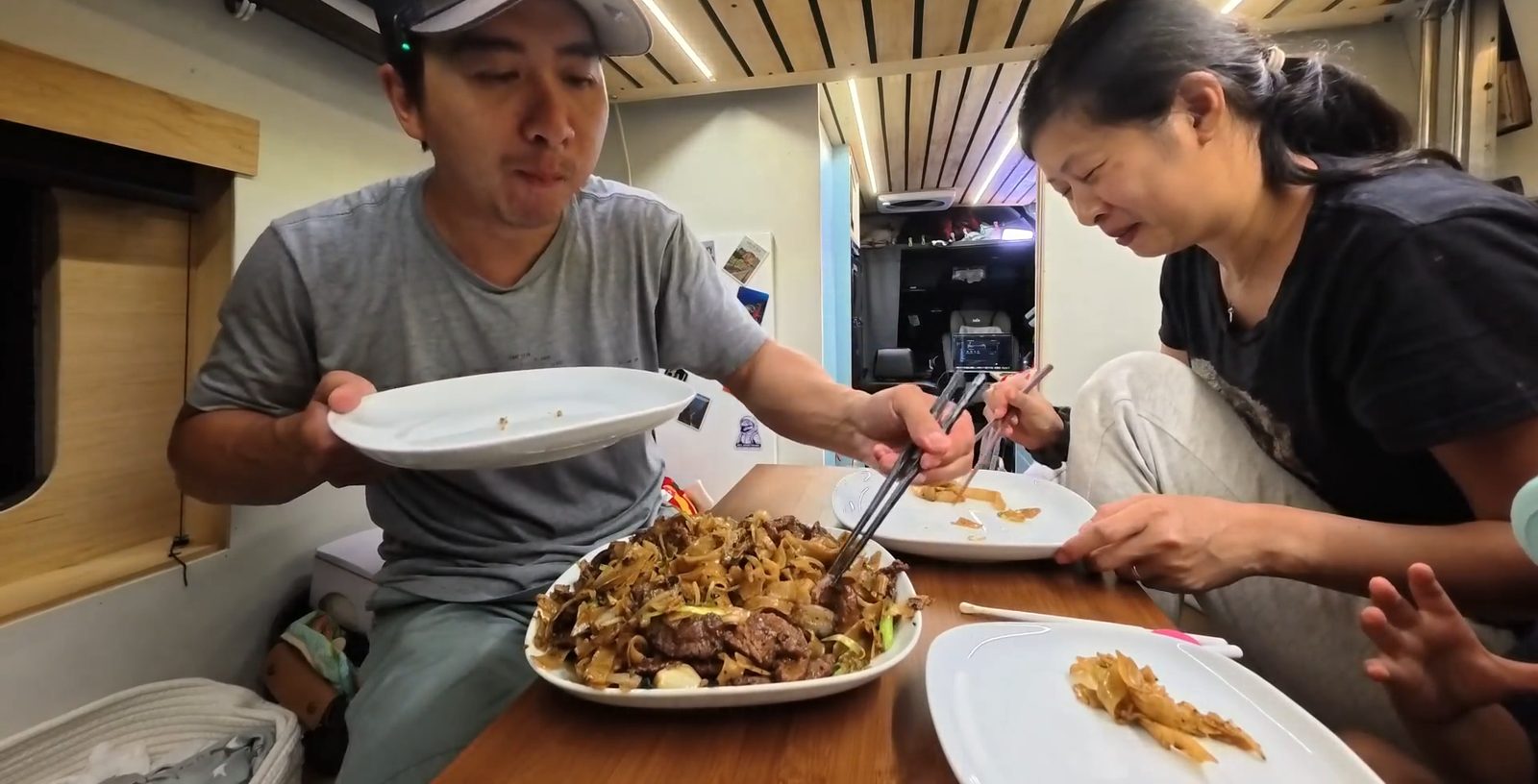 Michael and Rina eating beef chow fun at the table inside our van