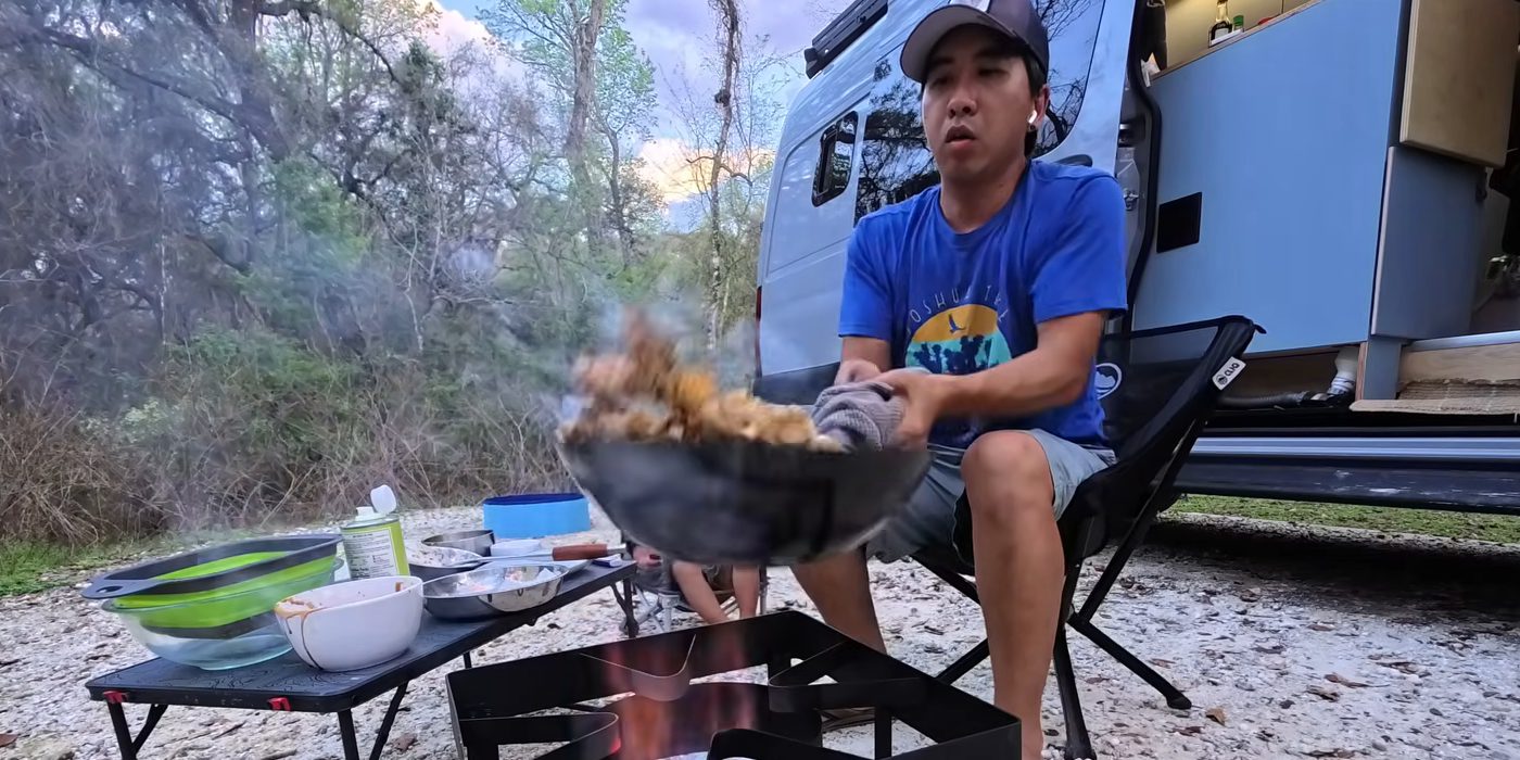 Michael tossing noodles in a smoking wok over the burner outside our van