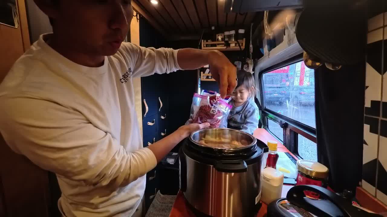 Michael dropping goji berries into the pressure cooker while Spencer watches from the bench in the van