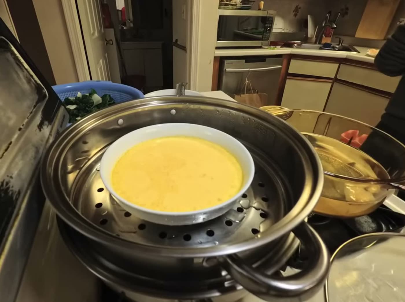 A bowl of beaten duck egg sitting in a stainless steel steamer on the stove