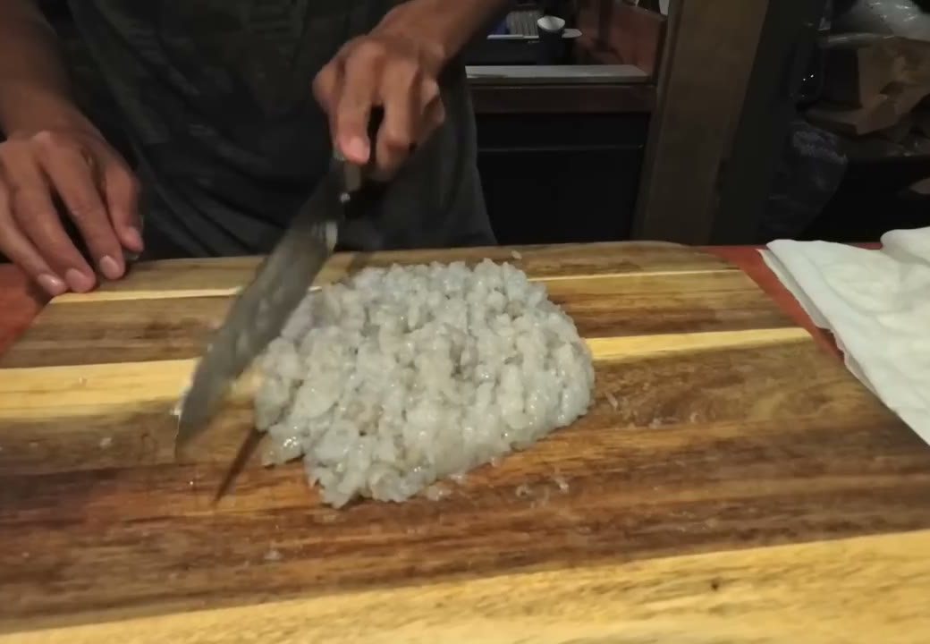 Chopping shrimp into a paste on a wooden cutting board in our van