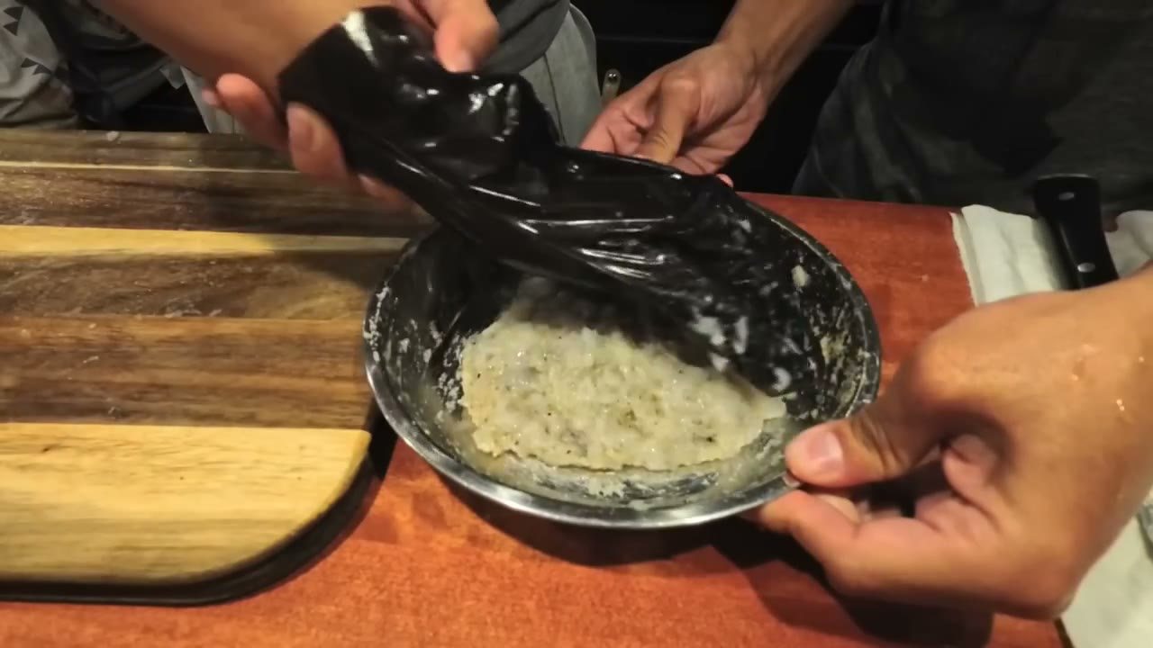 Mixing shrimp paste in a metal bowl with a plastic bag over the hand