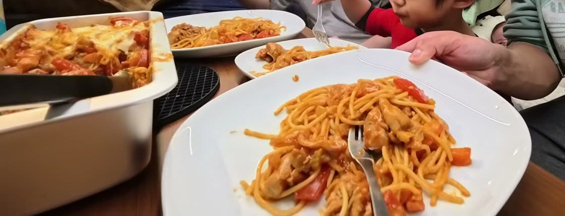 Plates of baked chicken spaghetti in tomato sauce on our van table, next to the baking pan