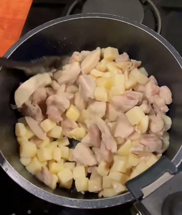 Cubed chicken and potatoes cooking in a pot on the stove in our van