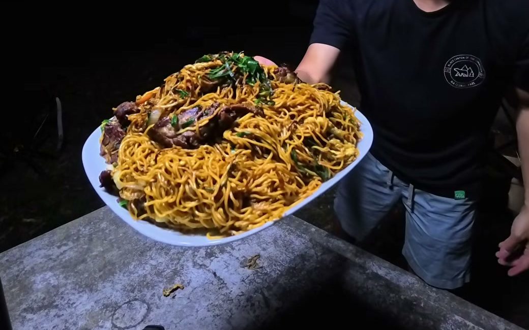 A plate of beef soy sauce pan-fried noodles held up at night at the Mammoth Cave campground