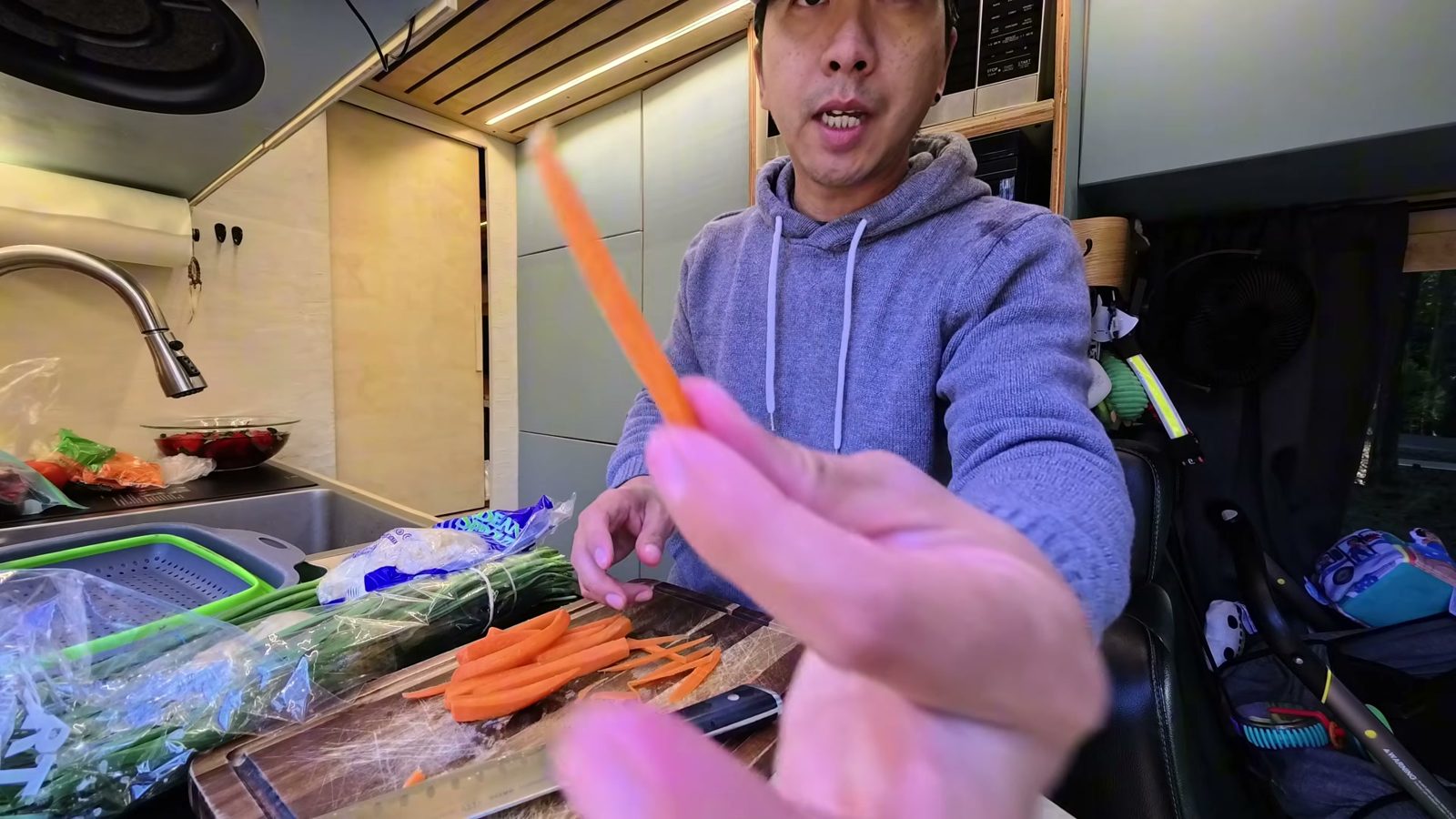 Slicing carrots into long thin strips on a cutting board in our van kitchen