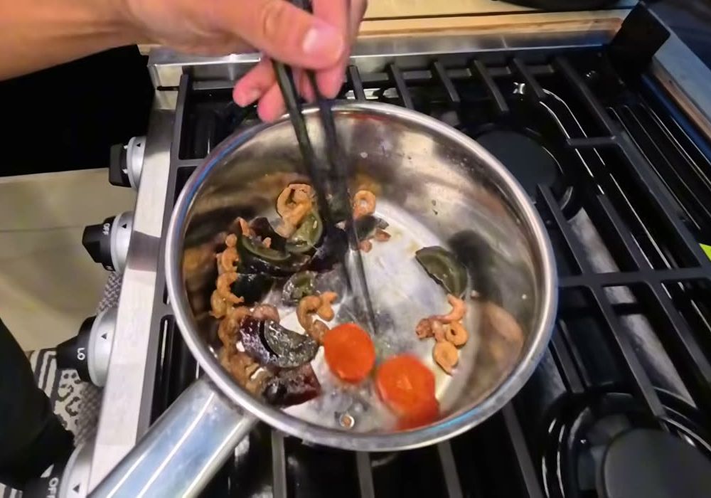 Dried shrimp, cut-up preserved duck egg and two orange salted egg yolks frying in a small pot
