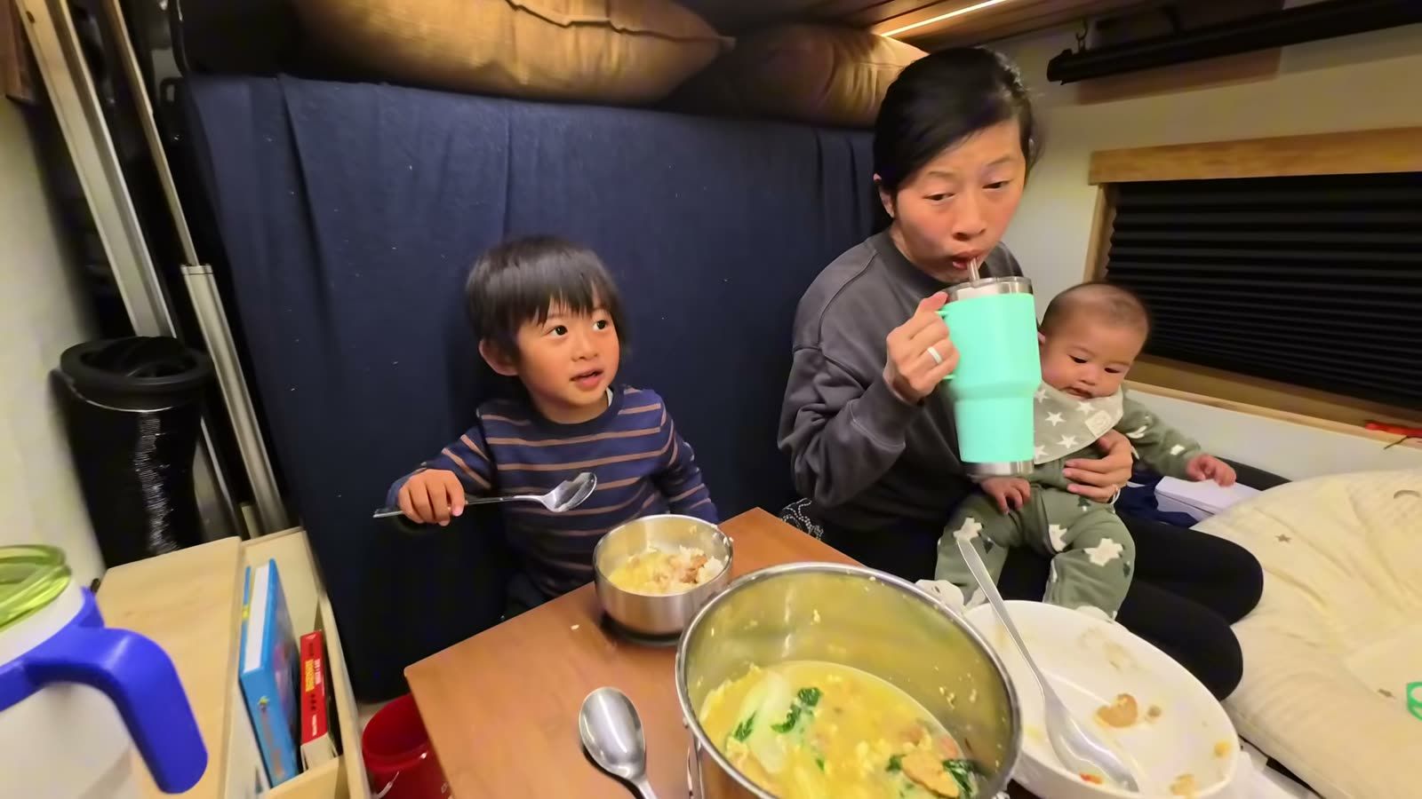 Spencer and Rina, holding Archie, at the van table with the pot of three egg soup