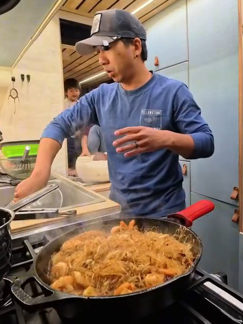 Michael cooking XO sauce vermicelli with shrimp in a cast iron pan in the van kitchen